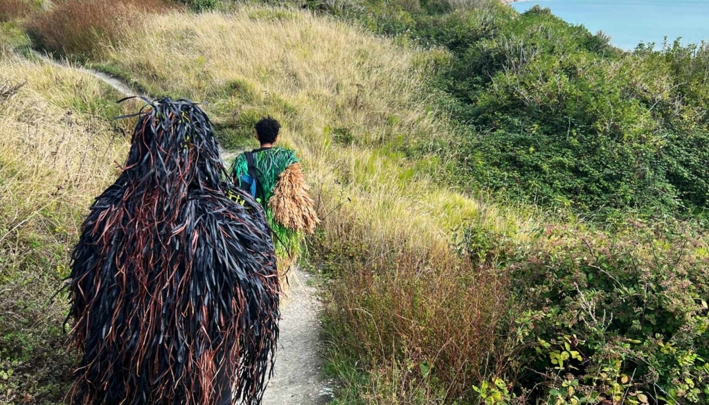 People walking along The Warren wearing costumes made of recycled and mixed media
