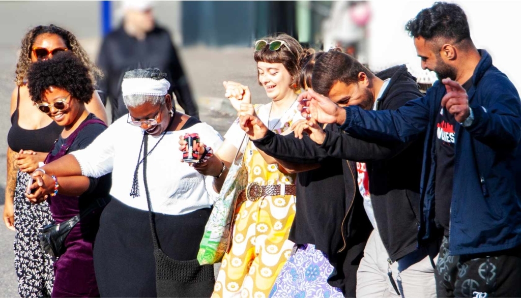 Diverse group of people linking hands and dancing in the street